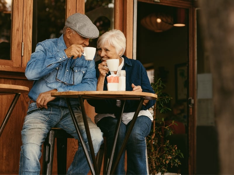 An elderly couple enjoys a cup of coffe together at an outdoor storefront